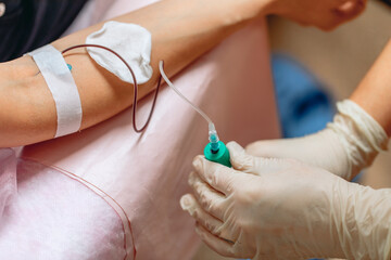 Gentle hands of a nurse taking blood from a patient's vein. Close-up. Gloves on the hands of a...
