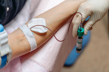 Gentle hands of a nurse taking blood from a patient's vein. Close-up. Gloves on the hands of a...