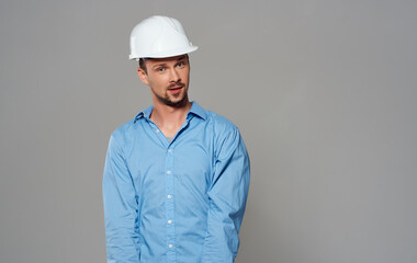 Emotional architect builder in a white helmet and in a blue shirt on an isolated background