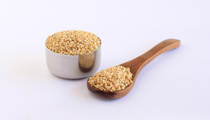 Steel-cut gluten free oats, which are in the category of whole grains, a healthy food, on a wooden spoon and in a steel bowl.