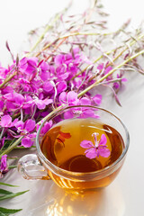 Fireweed herb known as blooming sally and tea in a cup, vertical image