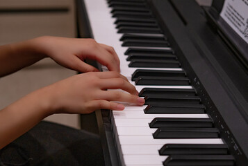 Fototapeta na wymiar Close-up of a music performer's hand playing the piano. Child learns to play the piano at home