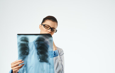 Doctor in glasses and in a medical gown with an X-ray in his hands