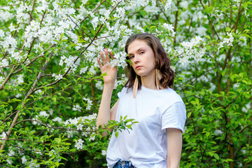 Obraz premium A spring walk. A girl walks through a blooming spring apple garden