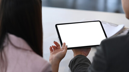 Close up view of business people using digital tablet and discussing strategy for company growth.