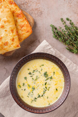 Cheese soup with thyme and bread on a beige background. Vegetarian food. Flat lay.