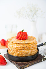 Homemade traditional thin pancakes with berries on a white background
