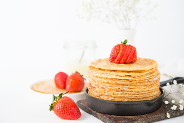 Homemade traditional thin pancakes with berries on a white background, Maslenitsa
