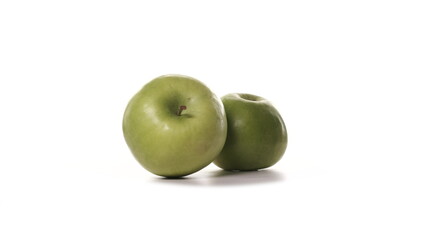 Two fresh green apples are spinning on white background. Freshly picked sour or sweet apples granny smith on turntable detailed view isolated.