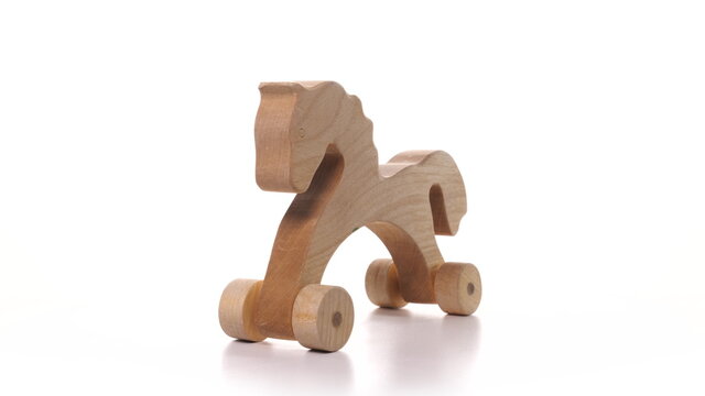 toy wooden horse on wheels is spinning on white background. Wooden craft on turntable rotation, children's toy detailed view isolated