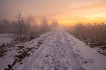 Fototapeta na wymiar The road leading dike between the lakes during the winter, frosty dawn