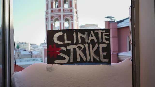 A poster with a demonstration and the inscription "Climate Strike" on a large drift of snow that lies on the bottom of a windowsill building, it snowed 65% of the monthly norm per day.