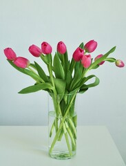 Bouquet pink tulips in glass vase stands on table on gray background. Easter day, March 8, women's day, birthday, gift, flowers for woman. Easter and spring greeting card Floristry Florist
