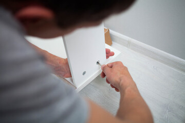 Close up of man hand, furniture assembler make flat pack white furniture assembly service at home.