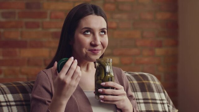 Close up portrait of young pregnant woman enjoying pickles smell, resting at home, slow motion