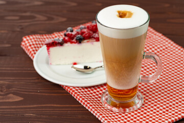 Cup of latte coffee with piece of berry cheesecake