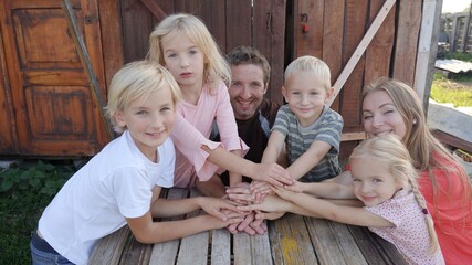 A friendly family joins their hands as a sign of joint success.