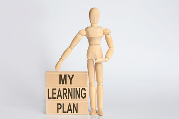 Wooden man shows with a hand text my learning plan concept on wooden block