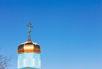 Dome of a rural Orthodox cathedral with a cross against a clear blue sky. Simple village church....