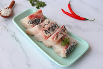  Uncooked boneless pieces of threadfin fish. Raw Dadha fish cubes placed on a blue plate. clean...