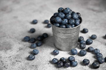 Fresh blueberries in a small metal bucket surrounded with some berries on a checked napkin. Top view. Rustic.