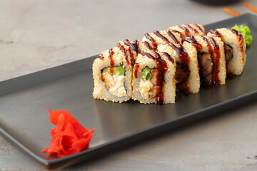 Sushi roll with sesame on black ceramic plate