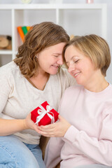 Homosexual couple of girls at home. Spouses give each other gifts and hug