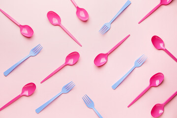 Plastic spoons and forks on color background