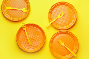 Plastic forks and plates on color background