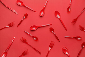 Plastic spoons and forks on color background