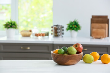 Bowl with fruits on table in modern kitchen
