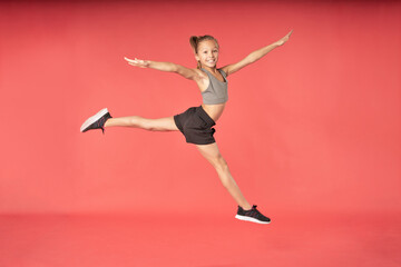 Adorable girl gymnast jumping against gymnast