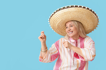 Dancing mature Mexican woman in sombrero hat on color background