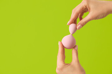 Hands with makeup sponges on color background