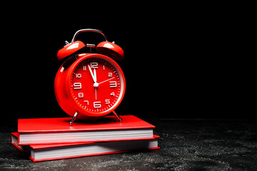 Alarm clock with books on black background