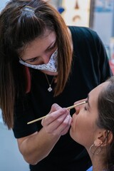 Woman applying makeup to a young girl