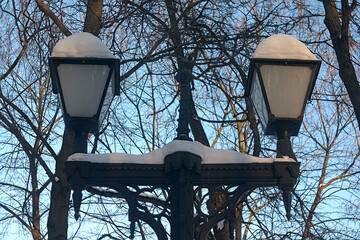 the lantern in the park is covered with snow