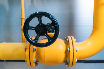 Industry and manufactory. Yellow pipe with black valve close-up