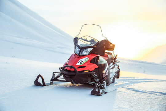 Kirovsk, Russia - FEBRUARY 1, 2021 red snowmobile brp lynx adventure lx 600 on a background of snowy mountains on a sunny day. 