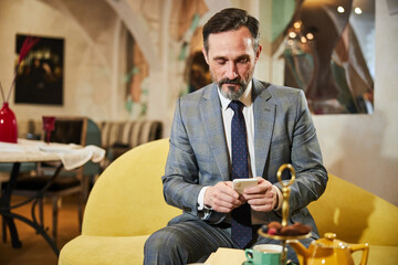 Busy gentleman in looking at his phone in lounge