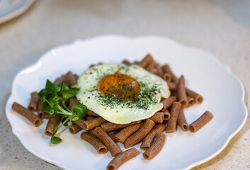 Fried egg with buckwheat noodles  and arugula on white plate