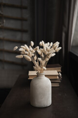 Rabbit bunny tail grass bouquet in pot, books stack on table