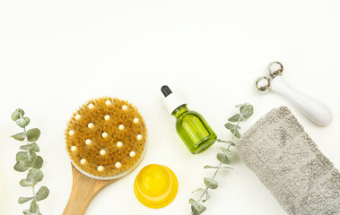 Face oil and face roller, brush for dry massage and a cotton towel lie on a wooden tray