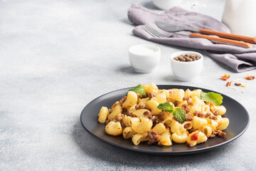 Stewed pasta with minced beef and vegetables, macaroni in Navy style on a plate. grey concrete background. Copy space.