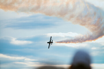 Aerial demonstration of a military airplane making a turn in the sky as it leaves a smoke trail,...