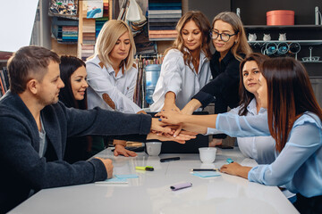 We are a team. Amazing creative group of successful office workers, as a sign of motivation and support, laying their hands on top of each other in a creative environment. Team suppost concept