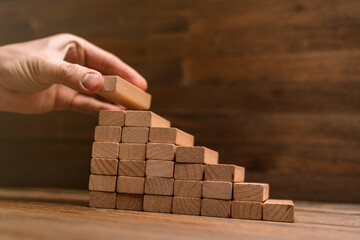 Obraz premium Business concept - hand builds a ladder from wooden blocks. Driving business at the peak concept.