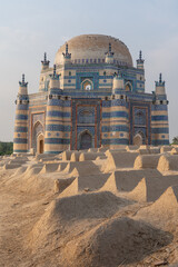 Sunset view of beautiful ancient medieval blue tomb of Bibi Jawindi with traditional graveyard in foreground in Uch Sharif, Bahawalpur, Punjab, Pakistan 