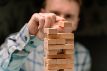 Business man in a shirt builds a tower of wooden blocks as a symbol of development and planning in business, a strategy for success