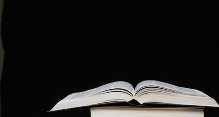 On a black background lies an open book. Concept education